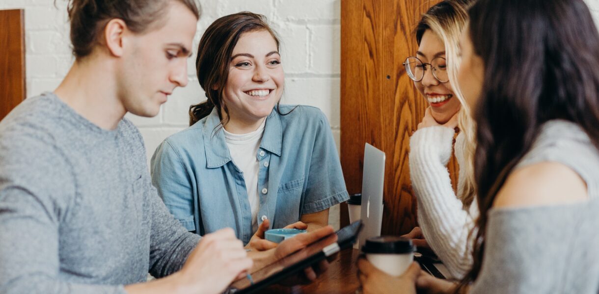 People sitting together. A trainer (freelancer) shows them a few skills on a tablet.