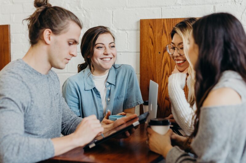 People sitting together. A trainer (freelancer) shows them a few skills on a tablet.