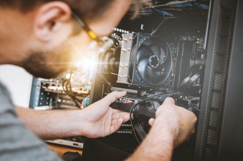 A man works as a freelancer and tries to fix a computer.