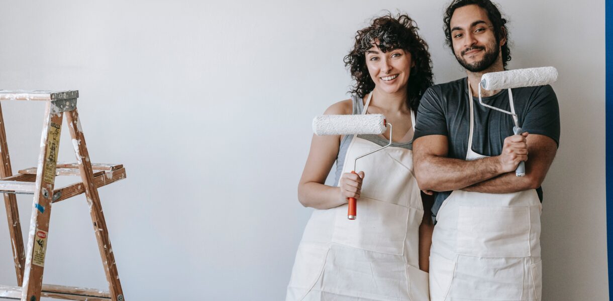 A woman and a man stand in front of a wall they want to paint