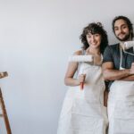 A woman and a man stand in front of a wall they want to paint