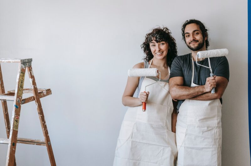 A woman and a man stand in front of a wall they want to paint