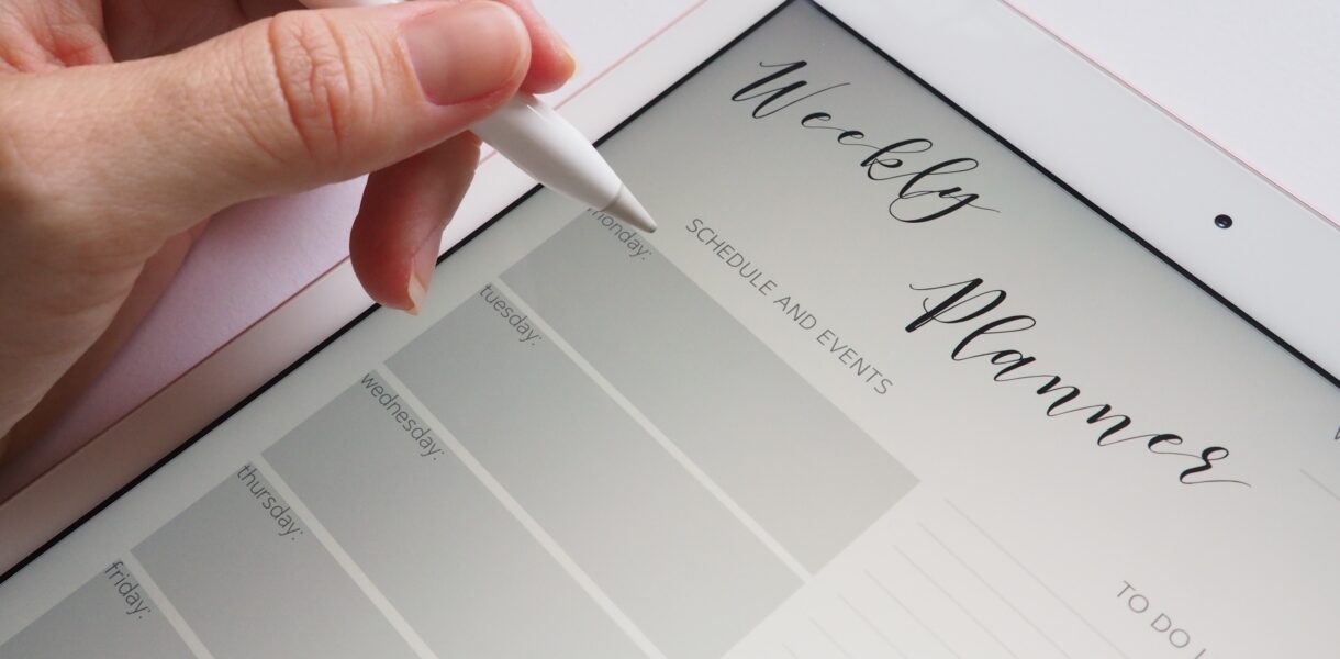 Person holds a pen in hand to write and save a new appointment on a tablet